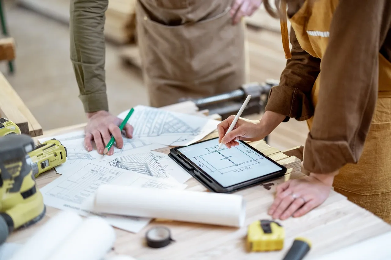 Planung eines Projekts mit Bauplan und Tablet in der Tischlerei